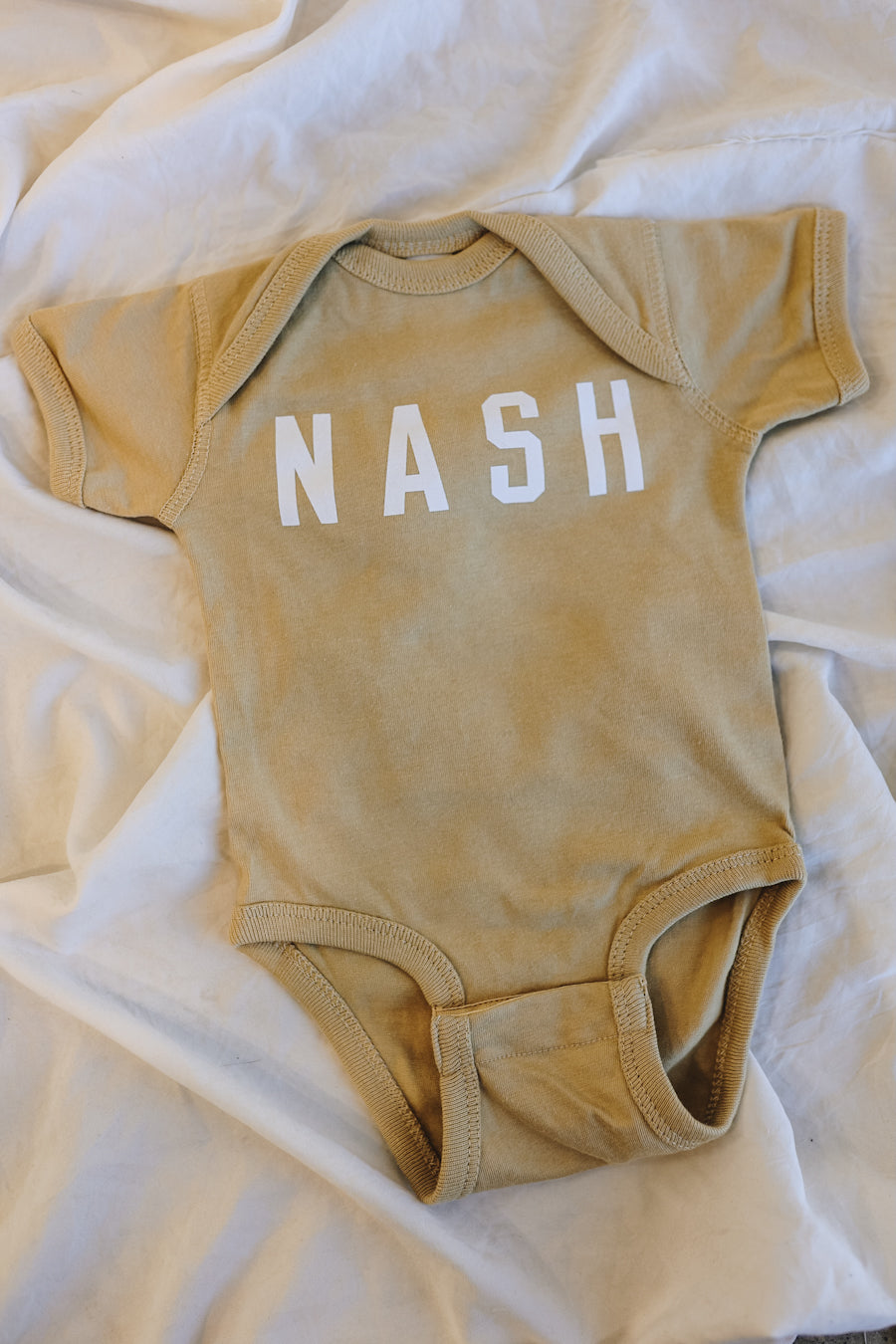 Light tan neutral color baby onesie.