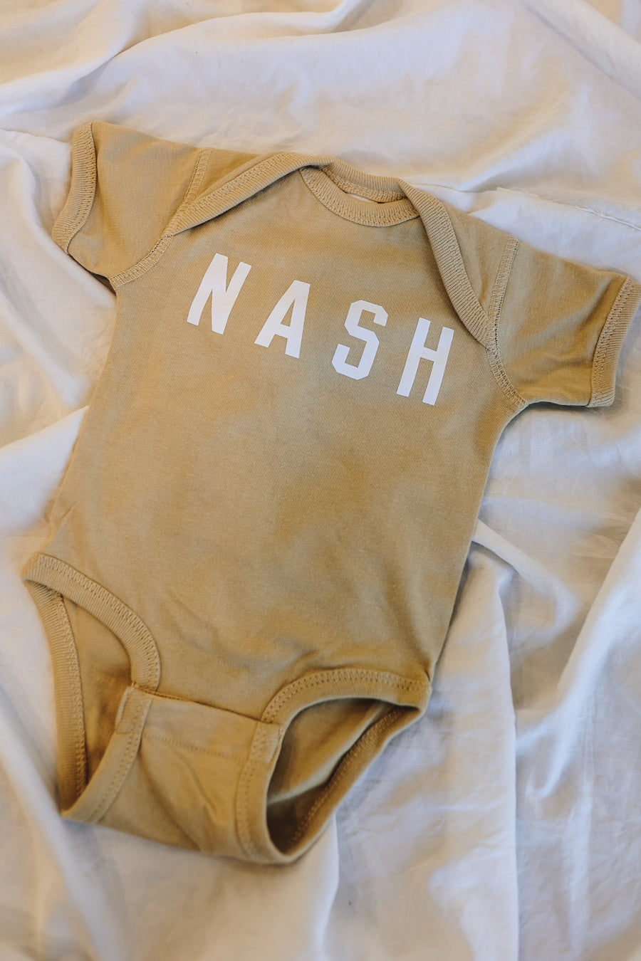 Light tan neutral color baby onesie.